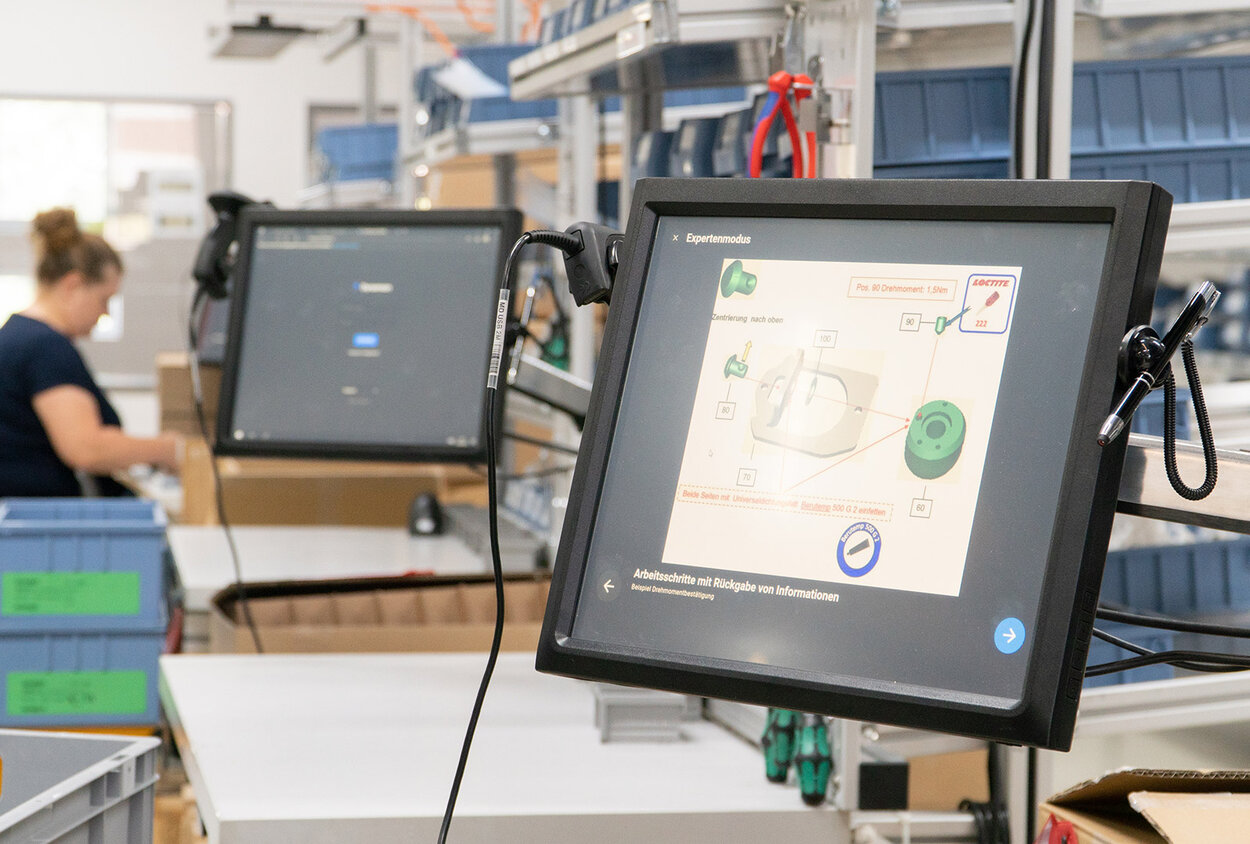 Mitarbeiterin befolgt digitale Arbeitsanweisungen auf dem Bildschirm